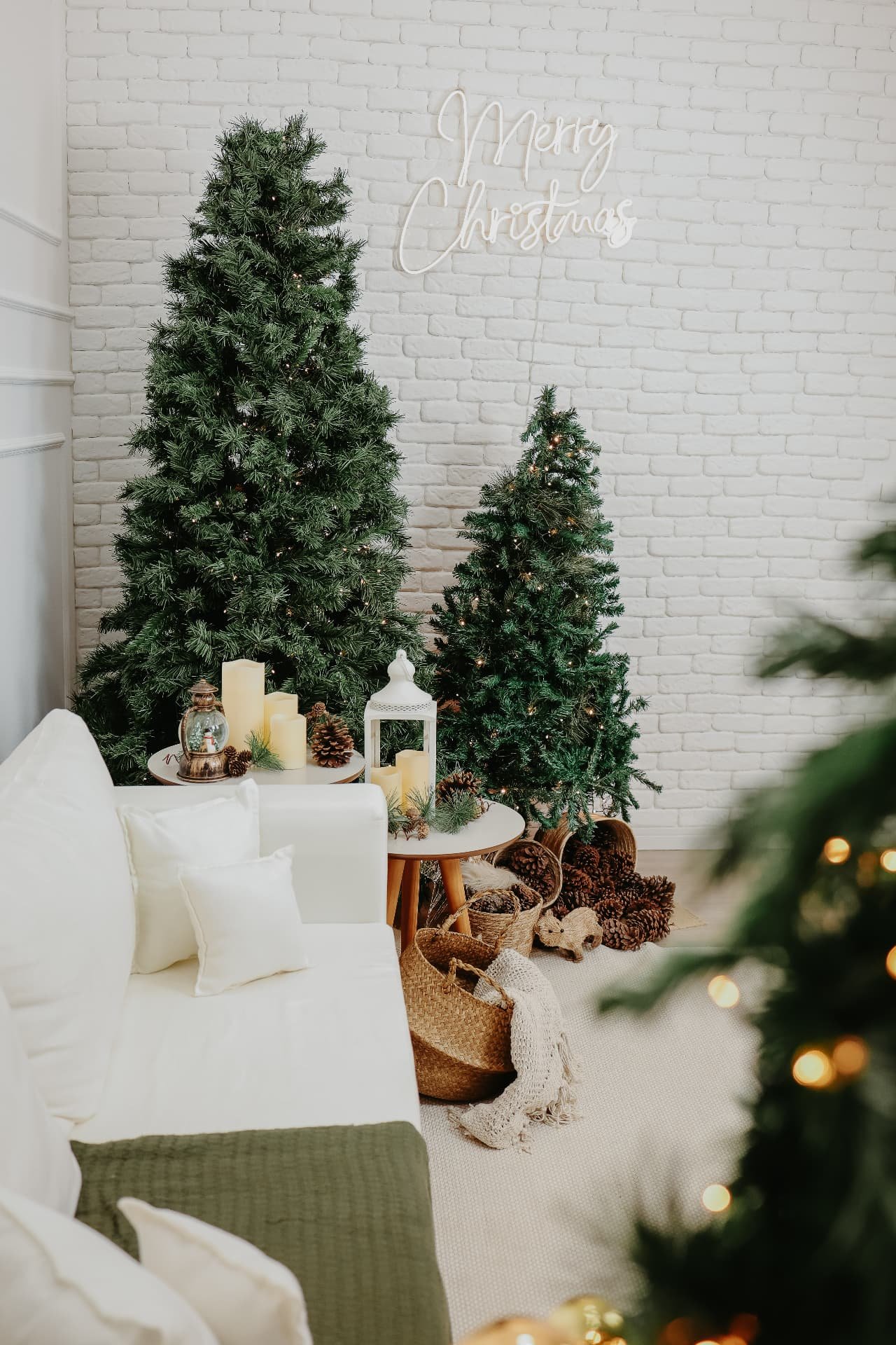 Cenário natalino com árvores decoradas, letreiro neon Merry Christmas e sofá branco